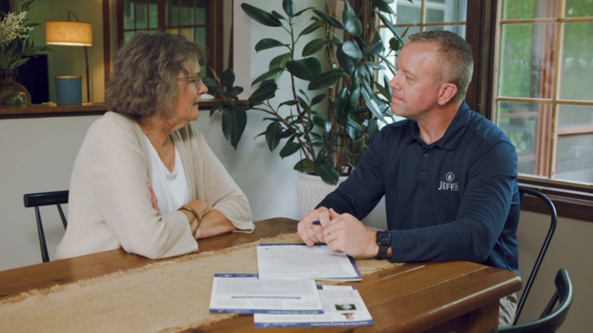 Jeff Buys Your House representative reviewing selling options and documents with a homeowner at her kitchen table.
