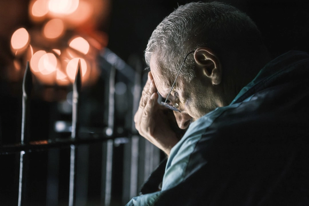 Elderly man with hand on forehead at night, stressed about his tenant occupied destroyed property.
