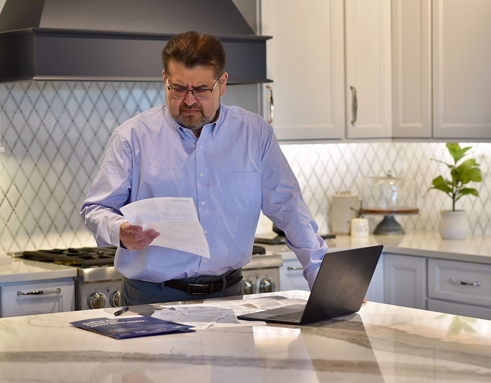 Homeowner reviewing financial documents in a kitchen